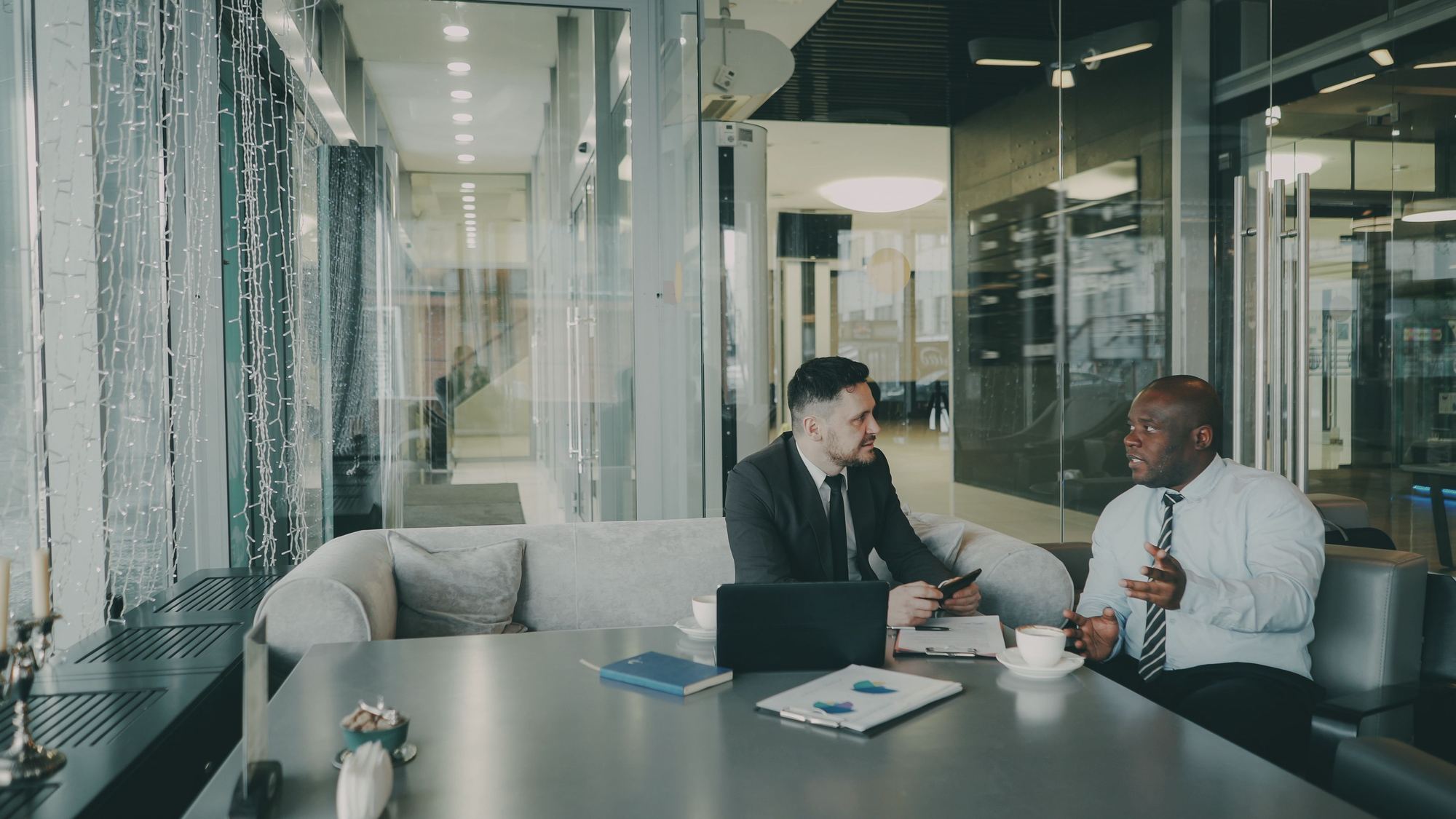 Two executives in a focused conversation in a glass-walled office