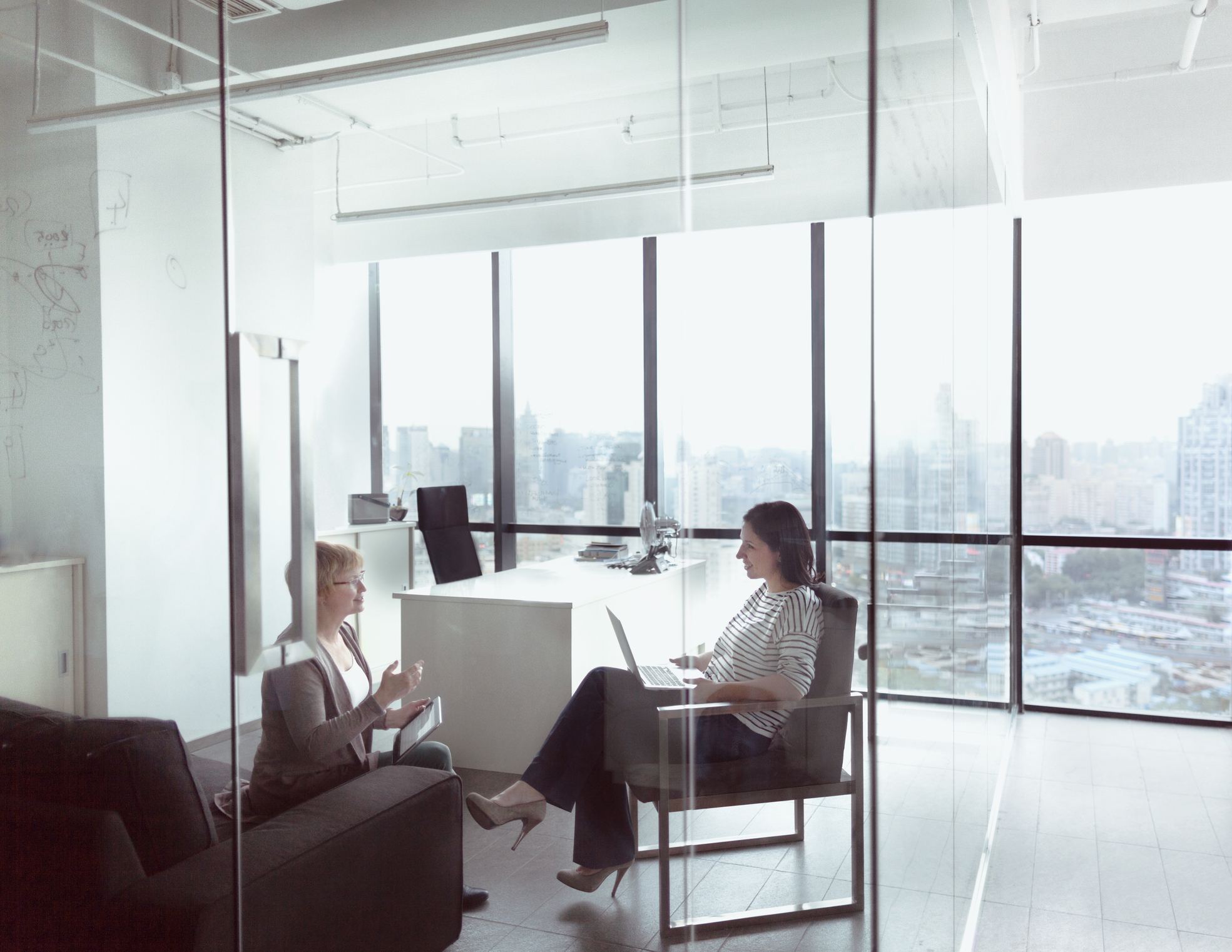 Two colleagues meeting in a bright glass-walled office